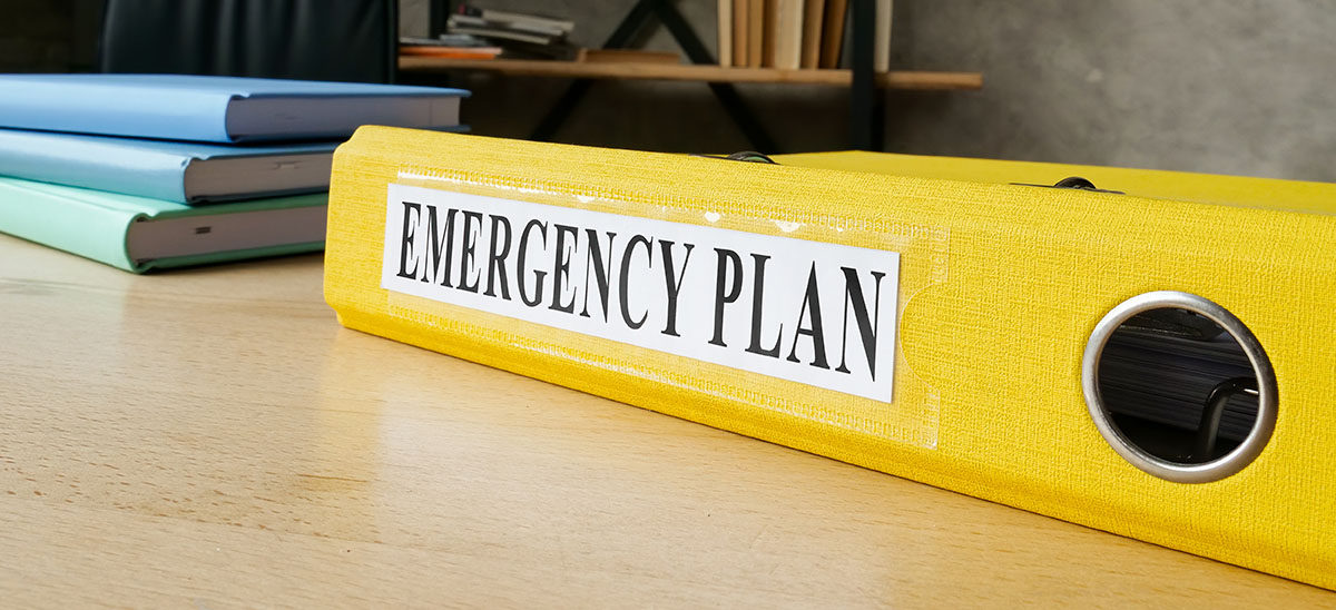 Yellow binder on desk with label "Emergency Plan"
